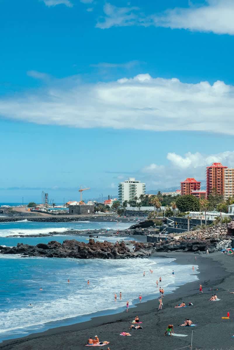 Relaxing day at Puerto de la Cruz's unique black sand beach with cityscape view.