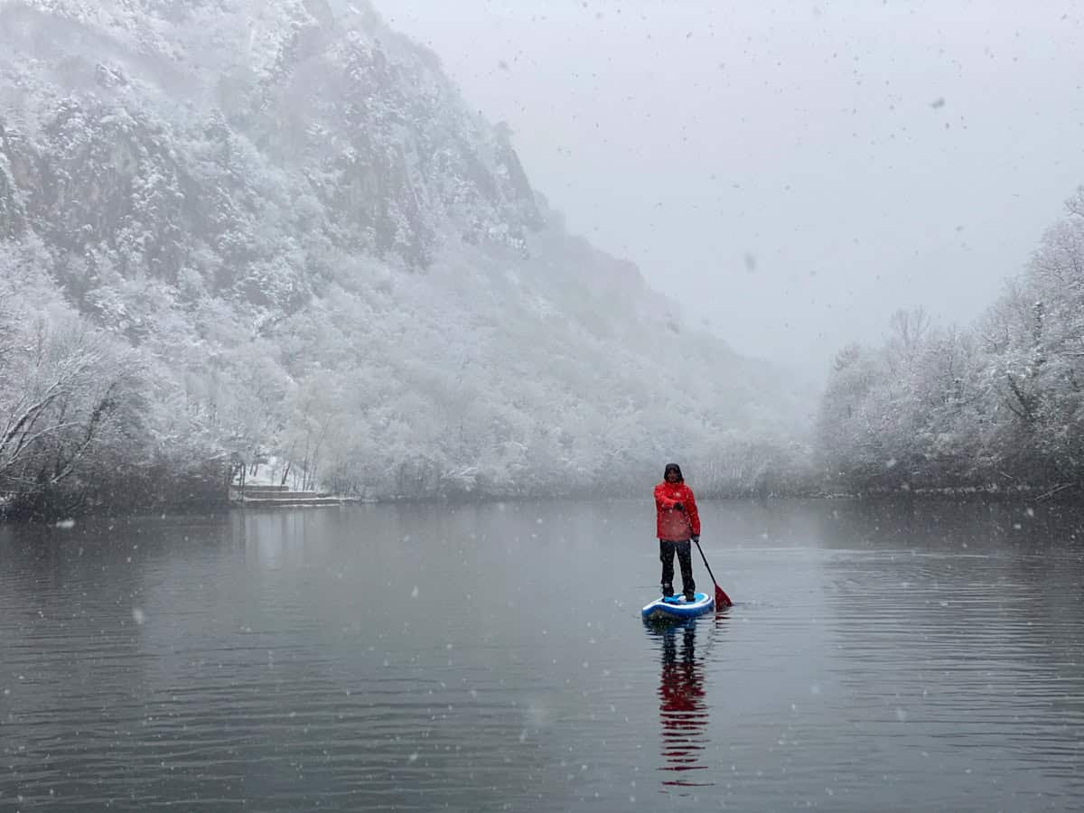 person in red hoodie standing on body of water during daytime