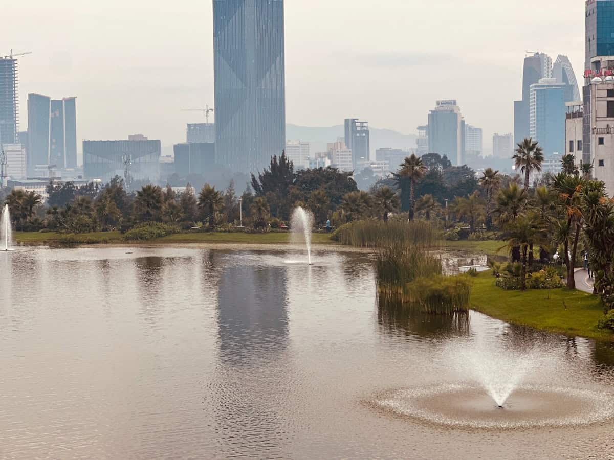A lake with a fountain in front of a city skyline