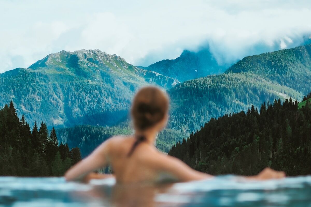 topless person in water near green trees during daytime