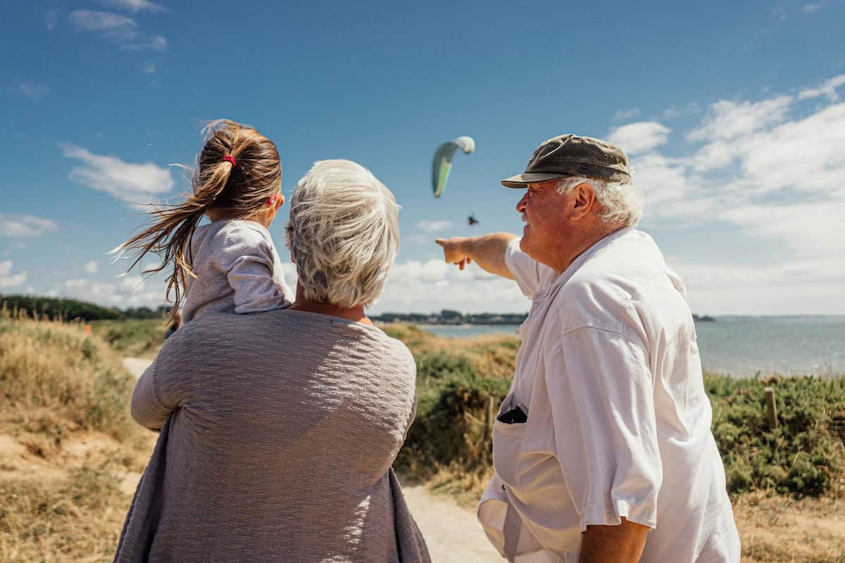 Family watching paraglider soar overhead