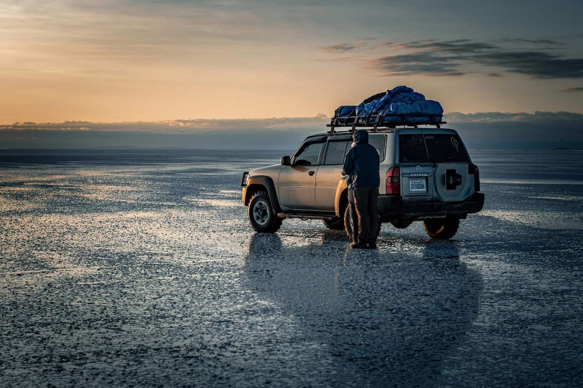 Adventurer with SUV on salt flats
