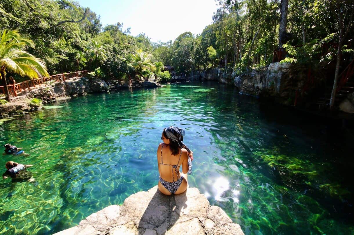 woman in black bikini standing on rock near river during daytime