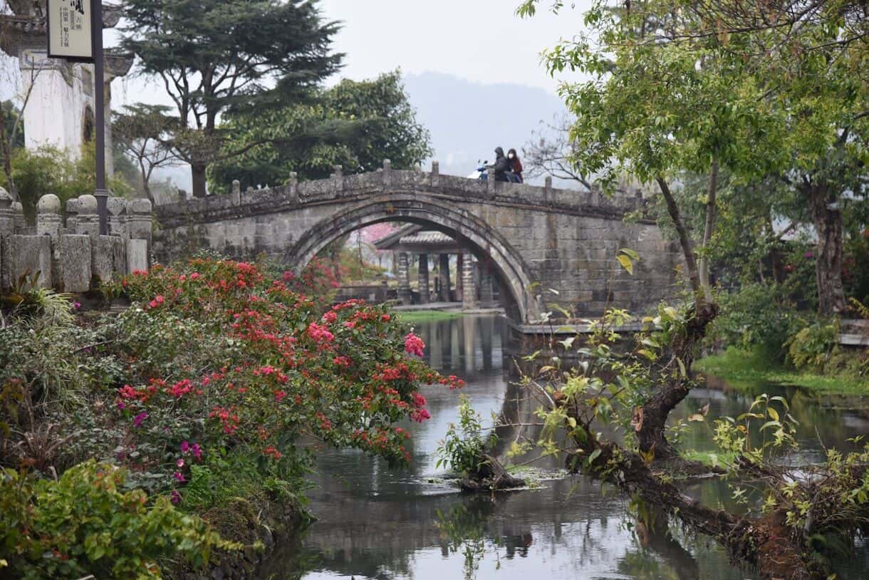 Calming Locations That Prove A Trip To Asia Doesn't Have To Be Hectic - Frayed Passport - Yunnan Province, China - a bridge over a river with people on it