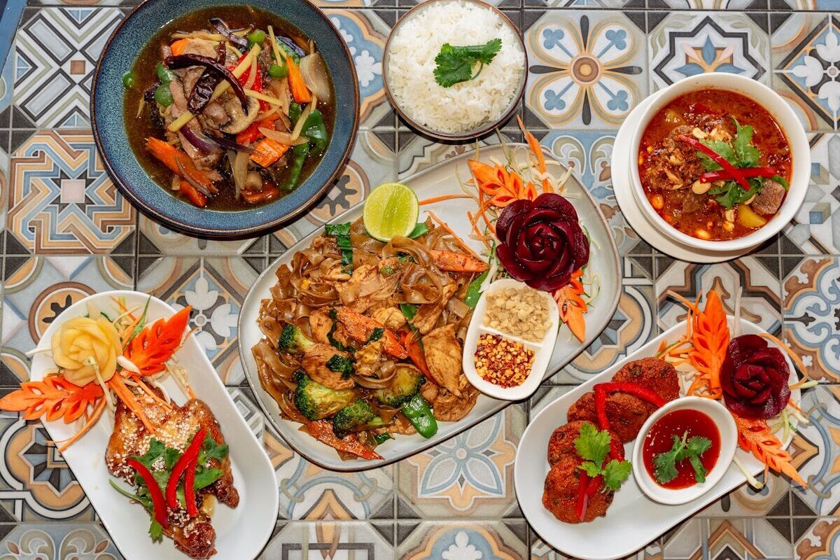 Getting Used to Thai Food As a Digital Nomad in Bangkok - Frayed Passport - A spread of delicious thai dishes on a patterned surface.